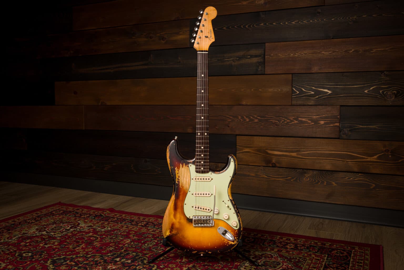 Custom Shop Frusciante Stratocaster upright on a stand against a timber wall